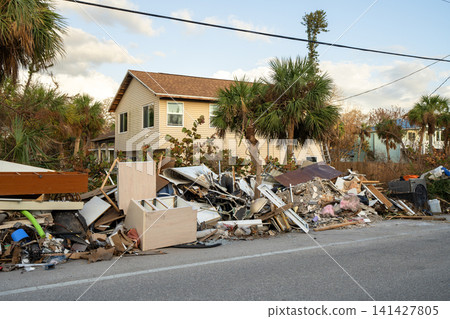 Cleanup efforts after hurricane in Florida. Piles of broken furniture, household debris and construction waste line streets of Manasota Key, showing severe impact on local homes and infrastructure Cleanup efforts after hurricane in Florida. Piles of broken furniture, household debris and construction waste line streets of Manasota Key, showing severe impact on local homes and infrastructure 141427805