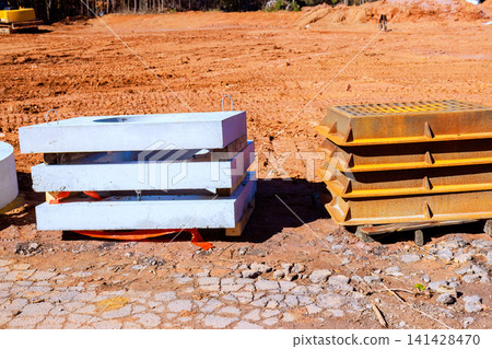 Workers prepare construction area with stacked concrete blocks metal plates on ground. Workers prepare construction area with stacked concrete blocks metal plates on ground. 141428470