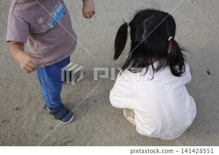 一個綁著雙馬尾的女孩在公園玩耍，還有一個孩子站在那裡。 141428551