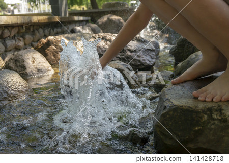 Child's hand splashing water in a rocky stream on a sunny day Child's hand splashing water in a rocky stream on a sunny day 141428718