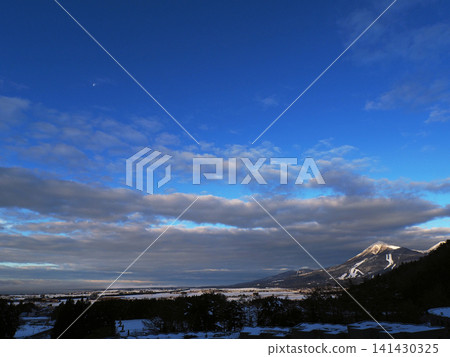 On a winter morning, the snow-capped Mount Bandai and the bright white moon shining against the blue sky are strikingly beautiful. On a winter morning, the snow-capped Mount Bandai and the bright white moon shining against the blue sky are strikingly beautiful. 141430325