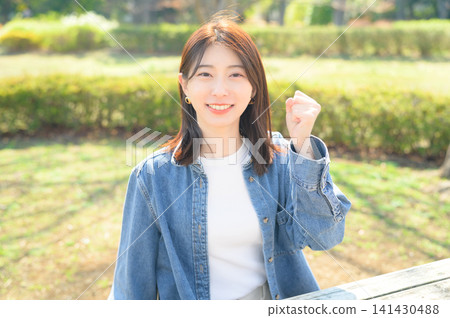 一名日本女子在公園裡擺出勝利姿勢 一名日本女子在公園裡擺出勝利姿勢 141430488
