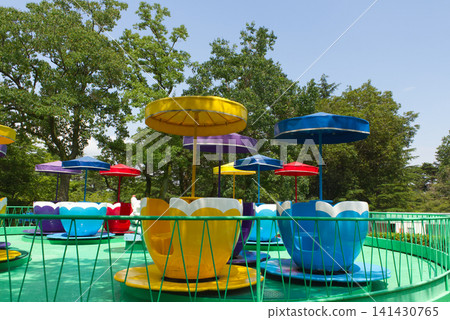 A retro amusement park scene featuring flower cups, colorful parasols, and coffee cup-shaped rides. A retro amusement park scene featuring flower cups, colorful parasols, and coffee cup-shaped rides. 141430765