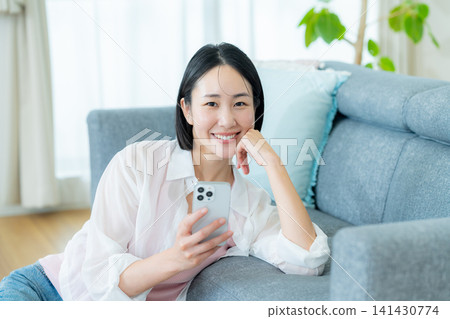 A woman who operates a smartphone in the room A woman who operates a smartphone in the room 141430774