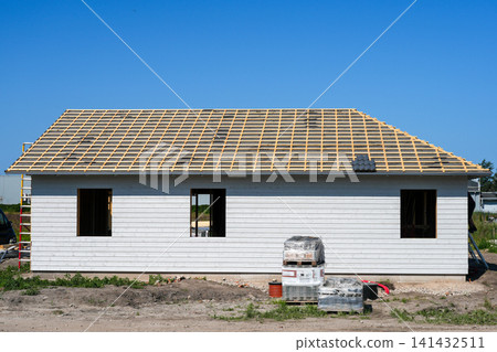 Modern timber frame house with roof battens under construction before final roofing installation phase Modern timber frame house with roof battens under construction before final roofing installation phase 141432511