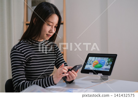 A woman thinking about investing while looking at her smartphone. A woman thinking about investing while looking at her smartphone. 141432575