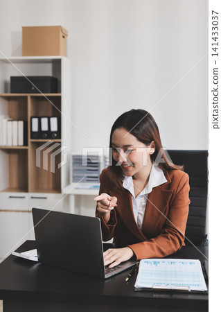 Asian businesswoman using calculator and working on laptop at modern office Asian businesswoman using calculator and working on laptop at modern office 141433037