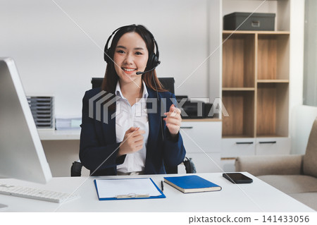 Smiling Asian Woman Telemarketing Agent with Headset Working at Smiling Asian Woman Telemarketing Agent with Headset Working at 141433056