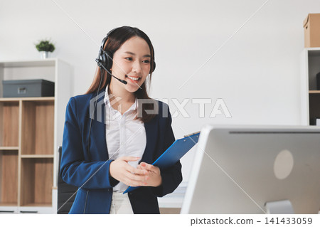 Smiling Asian Woman Telemarketing Agent with Headset Working at Smiling Asian Woman Telemarketing Agent with Headset Working at 141433059