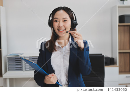 Smiling Asian Woman Telemarketing Agent with Headset Working at Smiling Asian Woman Telemarketing Agent with Headset Working at 141433060