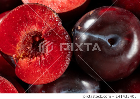 Close-up of a halved ripe plum showing juicy red flesh Close-up of a halved ripe plum showing juicy red flesh 141433403