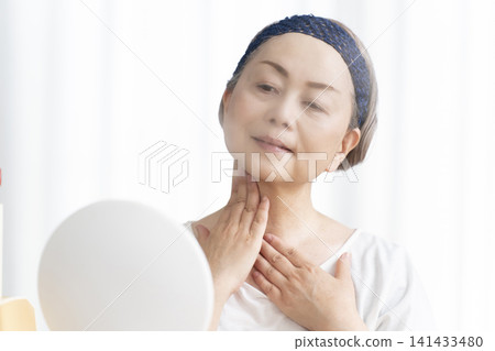 一位老年婦女使用臉部蒸氣機進行自我照顧。 一位老年婦女使用臉部蒸氣機進行自我照顧。 141433480
