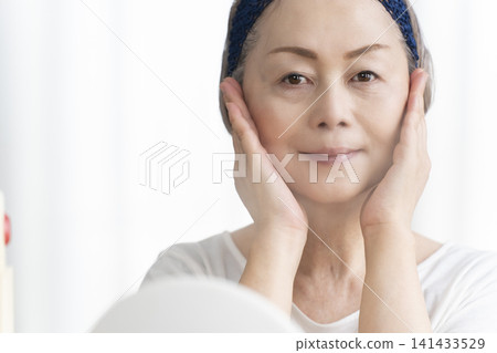 一位老年婦女使用臉部蒸氣機進行自我照顧。 141433529