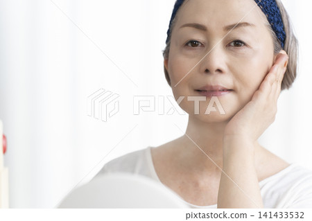 一位老年婦女使用臉部蒸氣機進行自我照顧。 一位老年婦女使用臉部蒸氣機進行自我照顧。 141433532
