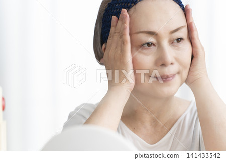 一位老年婦女使用臉部蒸氣機進行自我照顧。 141433542