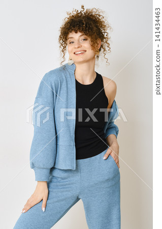 Woman posing in casual sporty blue outfit with curly hair in studio setting Woman posing in casual sporty blue outfit with curly hair in studio setting 141434463