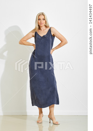 Model wearing dark blue dress in studio setup with neutral background Model wearing dark blue dress in studio setup with neutral background 141434497
