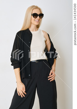 Model posing in indoor studio wearing black outfit and sunglasses Model posing in indoor studio wearing black outfit and sunglasses 141434500