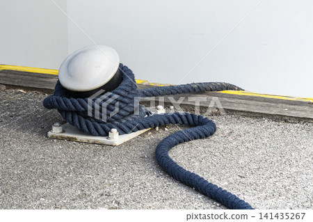 Blue braided rope wrapped around a metal mooring bollard at a marina, illustrating maritime work and dockside responsibilities. Blue braided rope wrapped around a metal mooring bollard at a marina, illustrating maritime work and dockside responsibilities. 141435267