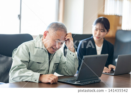 The company president holds his head in his hands in front of his computer. 141435542