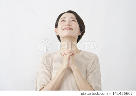A woman in her 40s with a smiling face against a white background, making a wish. A woman in her 40s with a smiling face against a white background, making a wish. 141436662