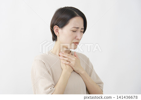 一名 40 多歲的女子，摀著喉嚨，似乎呼吸困難，背景為白色。 141436678
