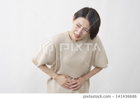 一位40多歲的女性，在白色背景下，腹部劇烈疼痛。 141436686