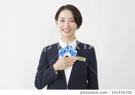 A smiling female staff member in her 40s with her hand on her chest against a white background. A smiling female staff member in her 40s with her hand on her chest against a white background. 141436700