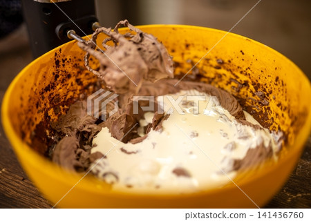 Closeup of creamy chocolate batter mixed with whipped cream in bright yellow bowl Closeup of creamy chocolate batter mixed with whipped cream in bright yellow bowl 141436760
