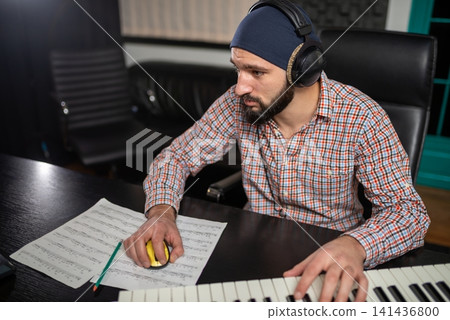 Sound engineer editing music at a studio workstation Sound engineer editing music at a studio workstation 141436800