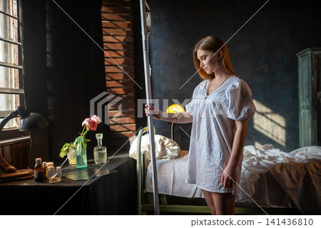 Female patient standing by her bed and holding an IV stand Female patient standing by her bed and holding an IV stand 141436810
