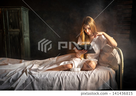 Close up portrait of a young woman reading a book in bed Close up portrait of a young woman reading a book in bed 141436815