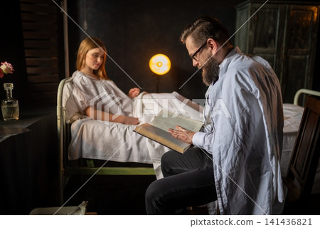 Bearded doctor reading a book near a lying female patient 141436821