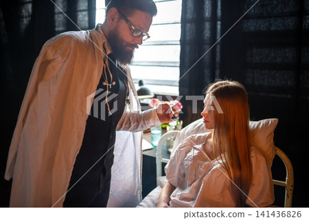 Doctor giving liquid medicine with a spoon to a patient Doctor giving liquid medicine with a spoon to a patient 141436826