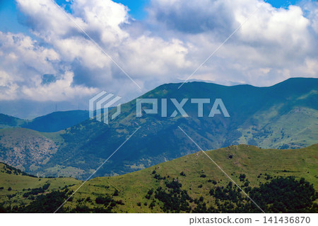 Wide mountain valley with grassy slopes and scattered trees Wide mountain valley with grassy slopes and scattered trees 141436870