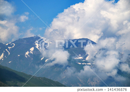 Snow-capped mountain range partially hidden by drifting clouds Snow-capped mountain range partially hidden by drifting clouds 141436876