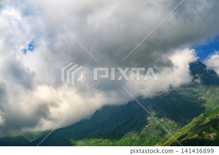 Clouds drift over jagged peaks, green valleys below Clouds drift over jagged peaks, green valleys below 141436899