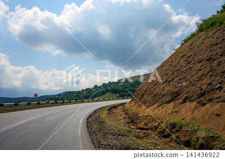 Road curves upward beside exposed earth Road curves upward beside exposed earth 141436922