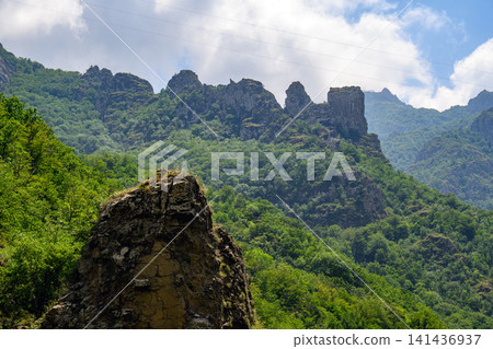 Weathered stone structure overlooks verdant valley Weathered stone structure overlooks verdant valley 141436937