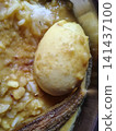 Macro view of boiled egg and crispy fried fish tail on yellow lentil rice base. Macro view of boiled egg and crispy fried fish tail on yellow lentil rice base. 141437100