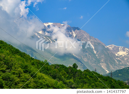 Clouds swirl around majestic mountain summits Clouds swirl around majestic mountain summits 141437797