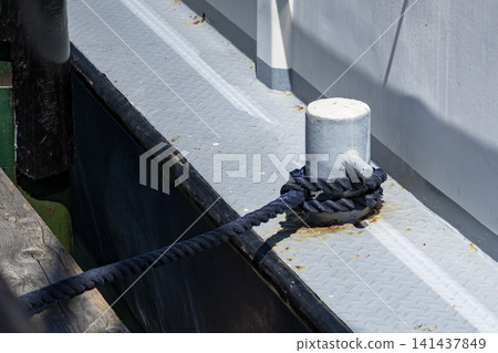 Mooring rope coiled around a bollard on a boat deck, illustrating nautical lifestyle in a marina setting and waterfront routines. Mooring rope coiled around a bollard on a boat deck, illustrating nautical lifestyle in a marina setting and waterfront routines. 141437849