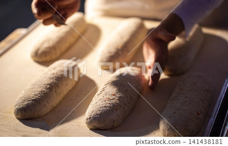 Hands shaping dough loaves on factory conveyor belt before baking process artisan bread production at bakery plant 141438181