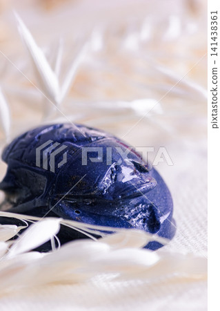 Macro shot of lapis lazuli scarab amulet on light linen fabric. Macro shot of lapis lazuli scarab amulet on light linen fabric. 141438361