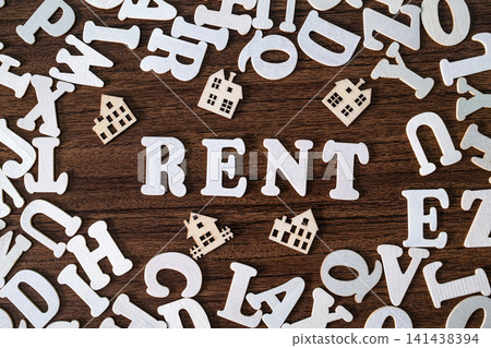 RENT word spelled with letter tiles and toy houses on scattered letters wooden background, real estate concept RENT word spelled with letter tiles and toy houses on scattered letters wooden background, real estate concept 141438394