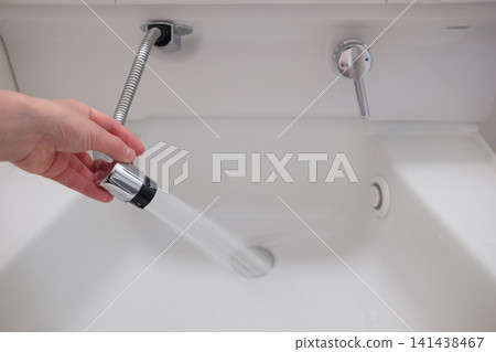 一位女士正在水槽水龍頭前洗手。 一位女士正在水槽水龍頭前洗手。 141438467