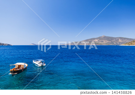 Two small boats tethered on a vibrant blue sea with clear skies Two small boats tethered on a vibrant blue sea with clear skies 141438826