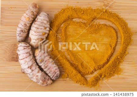 turmeric powder and roots on wooden background turmeric powder and roots on wooden background 141438975