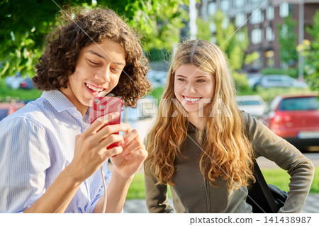 Happy teen boy and girl looking at red smartphone screen together 141438987