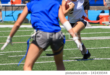 Running back running toward the defender during a girls flag football game Running back running toward the defender during a girls flag football game 141439344